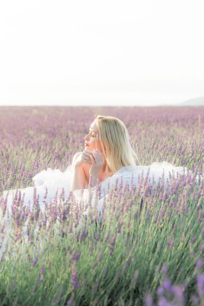 Fashion-inspired wedding portrait of a bride in a blue tulle gown surrounded by lavender, captured in warm natural light.