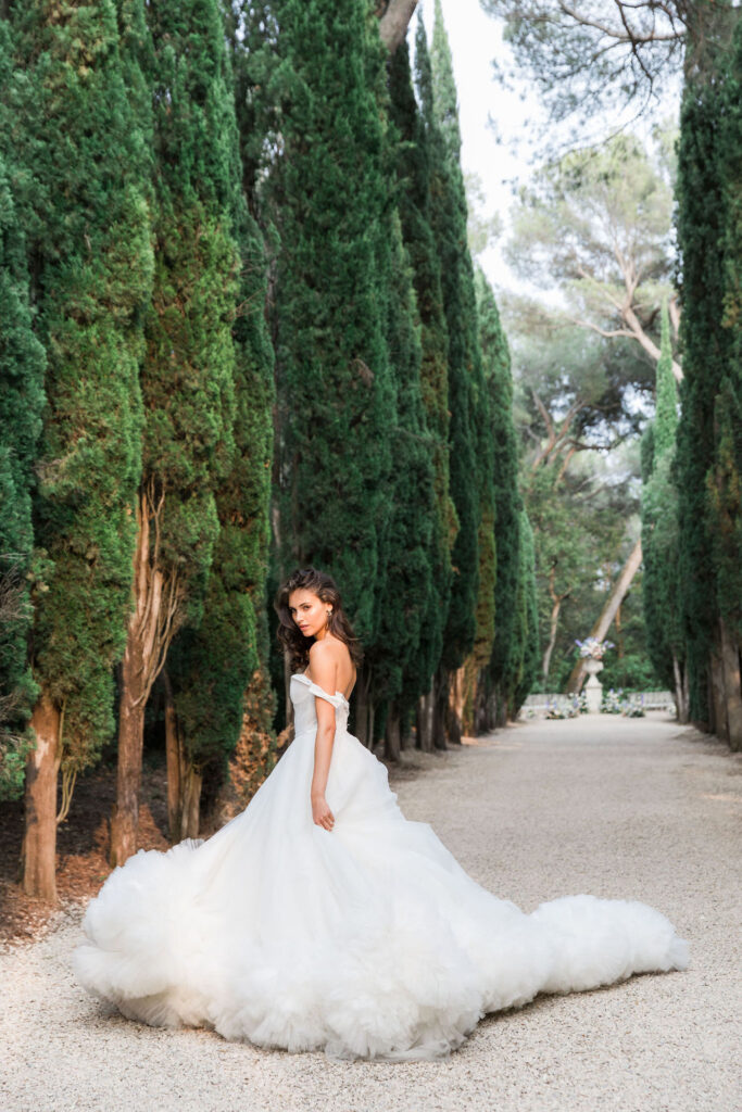 Bride lying in a lavender field wearing a flowing blue tulle gown, photographed in soft golden-hour natural light.