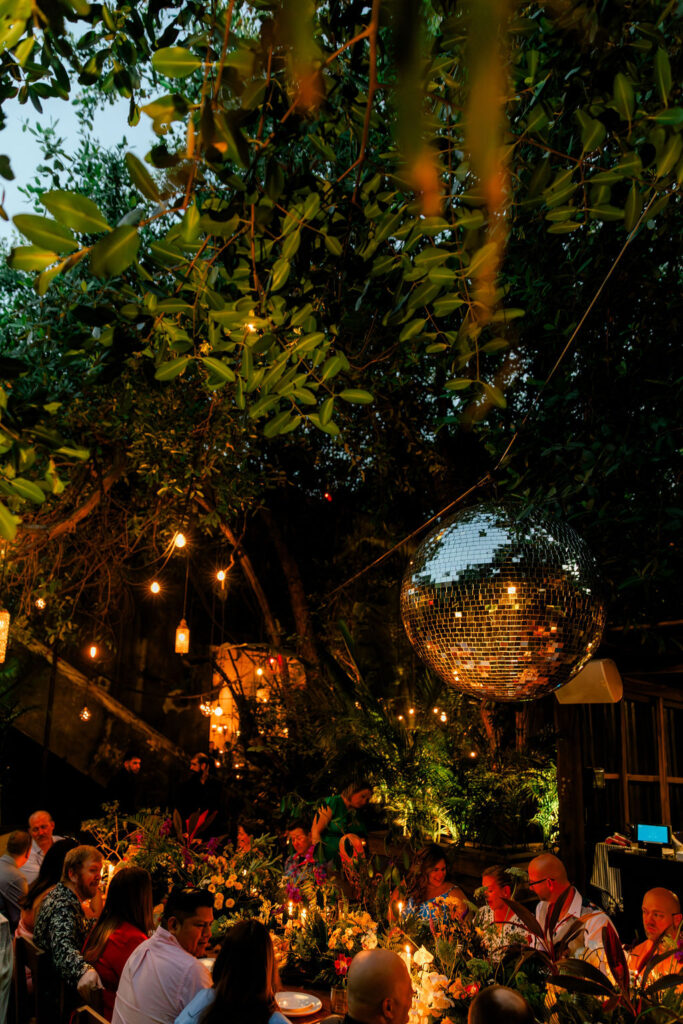 Outdoor wedding reception by the pool at night, illuminated with warm string lights under a tropical palapa roof.